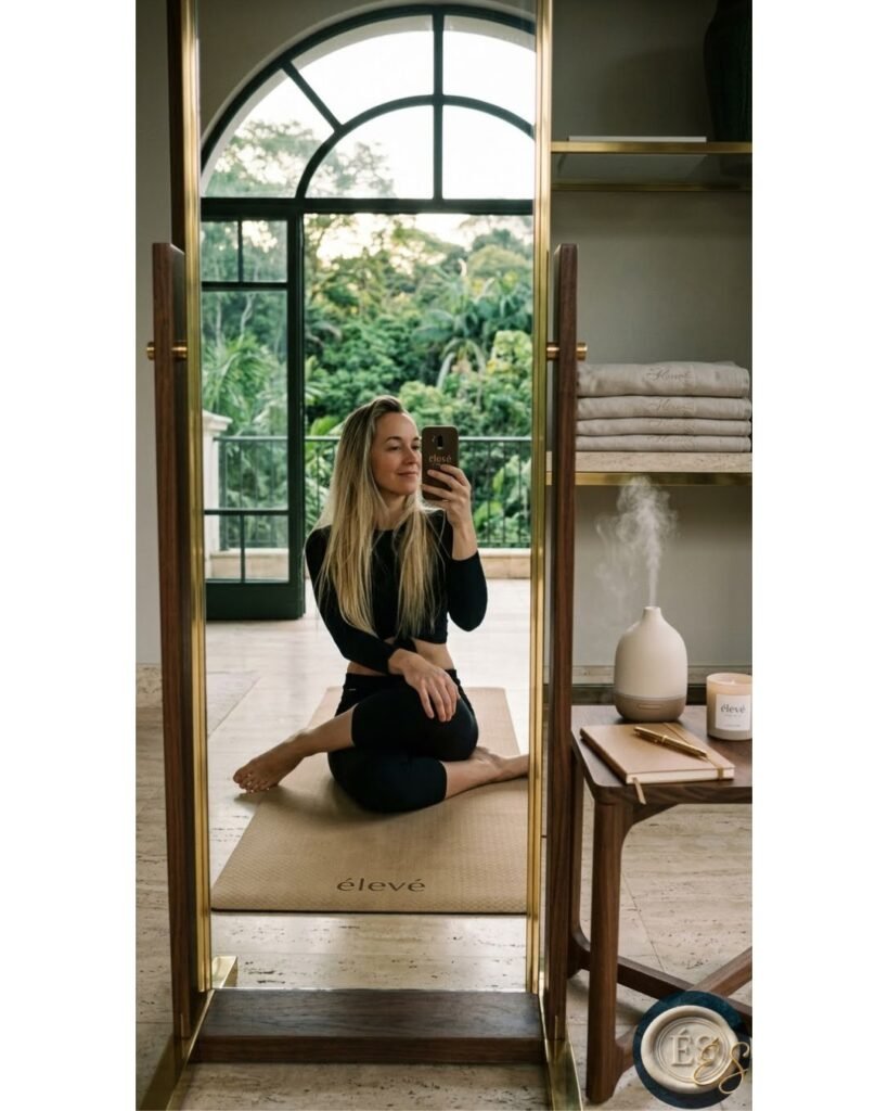 Fundadora de Élevé Society sentada frente al espejo sobre un tapete de yoga en un spa de lujo, practicando bionomía y enfoque mental.
