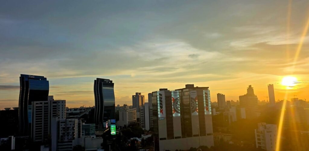Vista aérea panorâmica do nascer do sol sobre os modernos arranha-céus de Assunção, Paraguai, destacando a verticalização urbana.