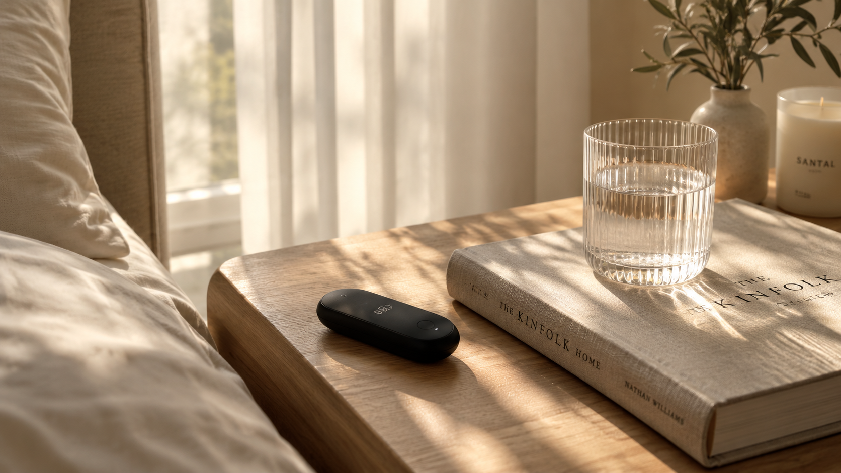 Lumen metabolic tracker on a wooden nightstand beside a glass of water and The Kinfolk Home book